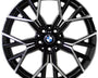 A metallic, multi-spoke alloy wheel with BMW logo at the center, designed for vehicles, displayed against a white background. The spokes feature a black and silver finish with intricate angles.