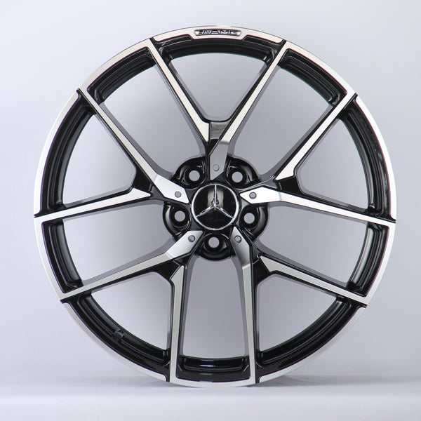 A metallic Mercedes-Benz wheel rim with five intricate spokes showcases the AMG logo, set against a plain white background.