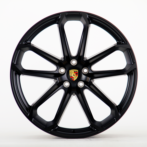 A black alloy wheel with multiple spokes and a central emblem displaying "Porsche" logo, seen on a plain white background.