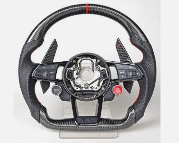 A carbon fiber car steering wheel, with multiple buttons including “VIEW” and “MENU” on the left and “RES” on the right, is displayed on a stand with a minimal background.