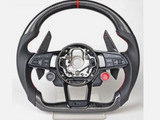A carbon fiber steering wheel, featuring electronic controls and paddle shifters, rests on a stand. It includes buttons labeled 