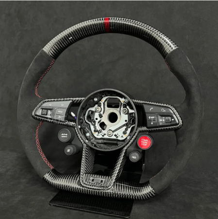 Steering wheel with carbon fiber texture and controls for audio, driving modes, and a red "Start Engine" button, sits against a dark backdrop. Central hub is exposed.