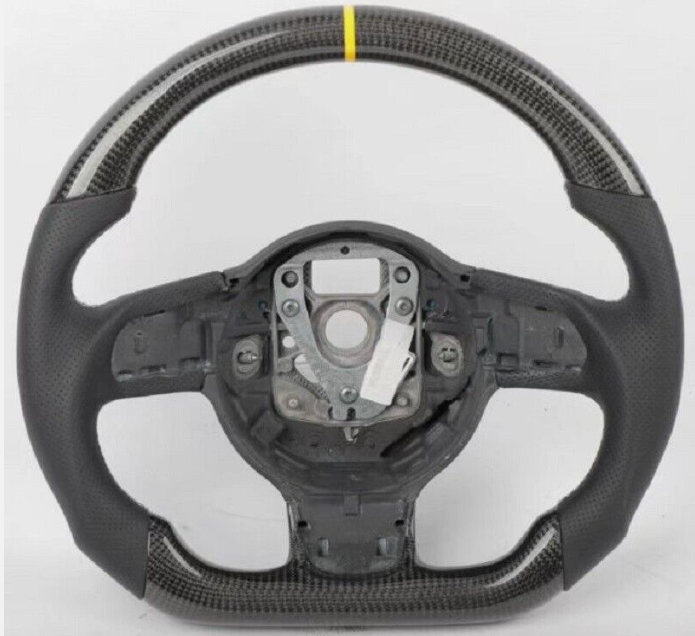 A carbon fiber steering wheel with a yellow stripe at the top, featuring a central mounting area, sits against a plain white background.