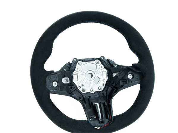 A black car steering wheel sits isolated against a white background, featuring an exposed central mechanism with screws and a textured circular outer grip.