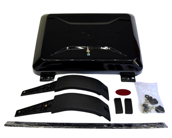 A black rectangular bike trunk lid with hinges sits surrounded by accessory parts: two curved brackets, a strip, and a bag of screws on a white background.