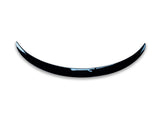 A shiny, curved black object resembling a crescent is positioned against a plain white background, giving a minimalist and modern appearance.
