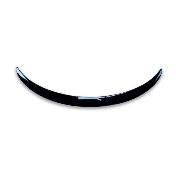 A shiny, curved black object resembling a crescent is positioned against a plain white background, giving a minimalist and modern appearance.