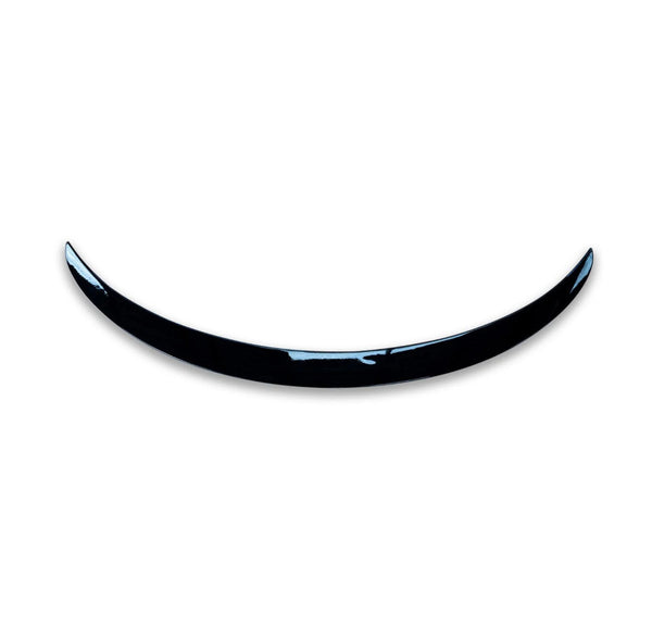 A shiny, curved black object resembling a crescent is positioned against a plain white background, giving a minimalist and modern appearance.