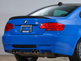 A blue BMW car is parked indoors, focused on its rear end with dual exhaust pipes. The license plate reads 