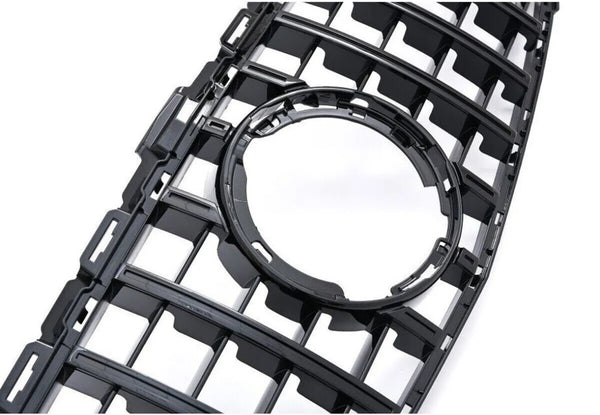 A black plastic grille featuring a series of rectangular openings surrounds a central circular cutout, set against a plain white background.