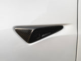 A triangular, carbon fiber car camera protrudes from a smooth, white vehicle surface, suggesting advanced technology integration for automotive safety and design enhancement.