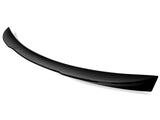 A glossy black car spoiler, slightly arched, is positioned against a plain white background, highlighting its sleek design and aerodynamic purpose.