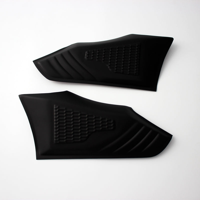 Two black rubberized grip pads lie flat, featuring textured patterns for grip enhancement, against a plain white background.