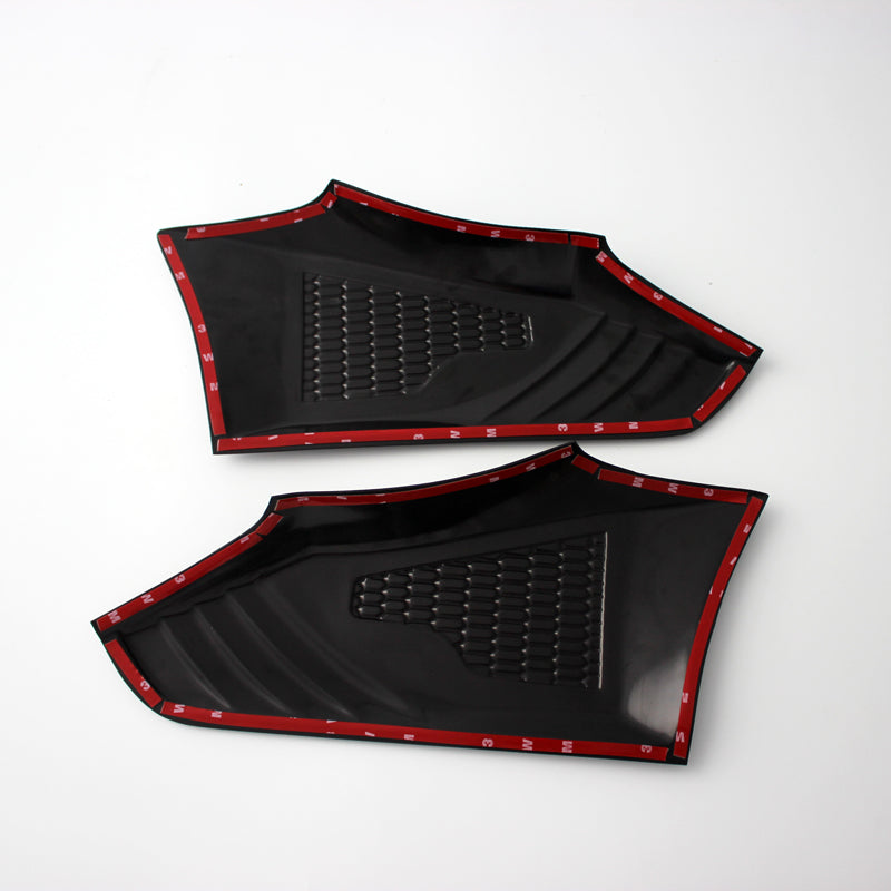 Two black plastic panels with textured surfaces, outlined by red trim tape, are positioned side by side on a plain white background.