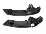 Two black plastic car light covers, each with a curved shape and mounting points, are positioned horizontally on a white background.