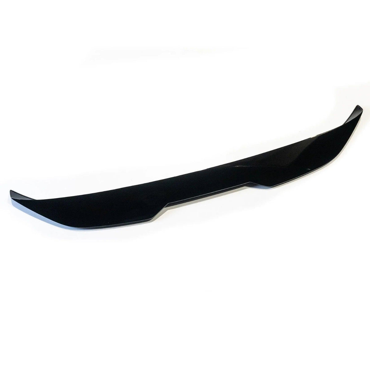 A sleek, black car front lip spoiler rests on a white background, featuring sharp edges and a subtle curvature designed to improve aerodynamics.