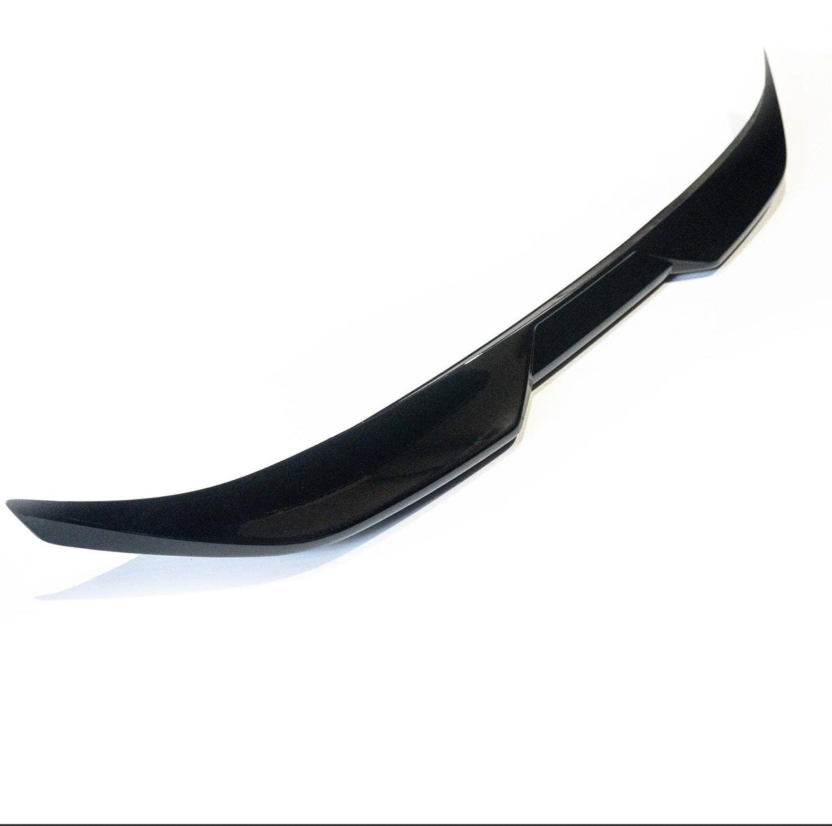 A glossy black car spoiler sits isolated against a plain white background. Its sleek, curved design features angular edges, suggesting it is an aerodynamic component for a vehicle's rear.