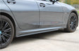A sleek, dark gray car is parked on a concrete surface. The vehicle features modern design elements, with distinctive rims and smooth side panels, set in an open outdoor area.