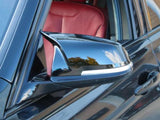 A sleek car side mirror reflects the sky and surroundings in a close-up shot, with a red leather car interior visible through the open window.