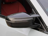 A black car side mirror is attached to a white vehicle. The window is open, revealing a red interior. The setting appears calm and focused on the vehicle's design features.