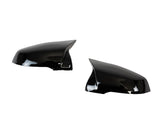 Two glossy black side mirror covers are displayed against a plain white background, angled toward each other, reflecting light on their smooth surfaces.