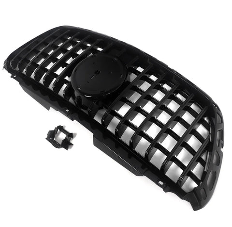 A black car grille with a mesh design lies on a white background. It features a central circular mount for an emblem, accompanied by an additional small attachment piece nearby.