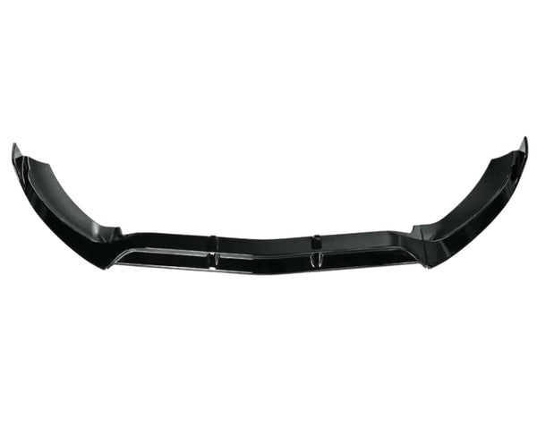A black car front splitter with aerodynamic contours lies on a white background, emphasizing its sleek, angular design intended to reduce air resistance and enhance vehicle performance.