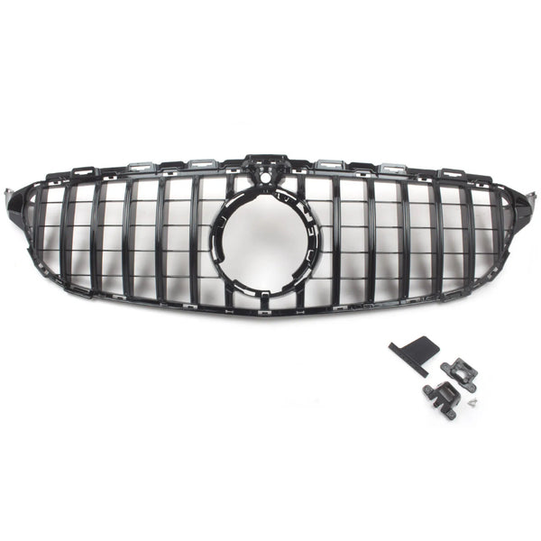 A black car grille with a circular center opening is positioned centrally; nearby, assorted mounting clips and brackets are laid out on a plain white surface.