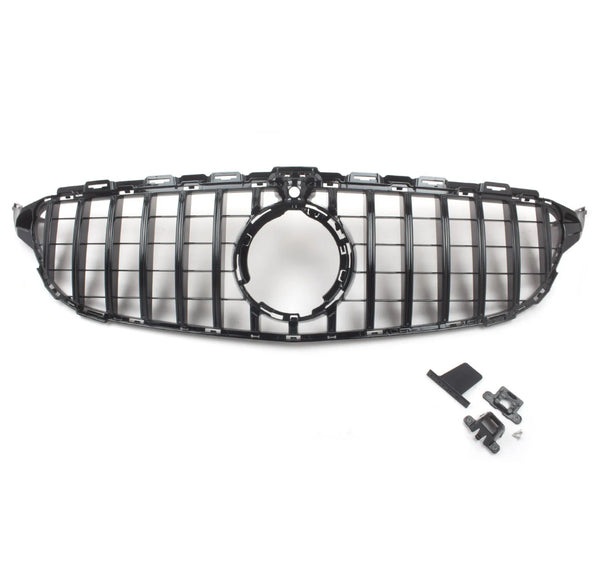 A black car grille with a circular center opening is positioned centrally; nearby, assorted mounting clips and brackets are laid out on a plain white surface.