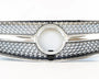 A shiny car grille features a prominent circular center, intricate mesh pattern, and chrome accents, positioned against a plain white background.