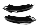 Two black, glossy aerodynamic car accessories lie side by side against a plain white background, showcasing their smooth, curved design and angular edges.