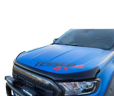 Blue truck front displaying "TESSER 4x4" on the hood, equipped with additional front bumper lights. The vehicle is parked against a plain, light background.
