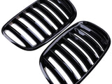 Black kidney-shaped car grilles with multiple vertical slats are placed side by side against a white background, showcasing their sleek, glossy finish.