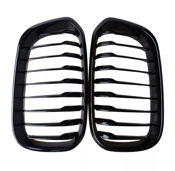 Two black kidney-shaped car grilles with horizontal slats are positioned side by side against a white background, emphasizing their glossy finish and symmetrical design.