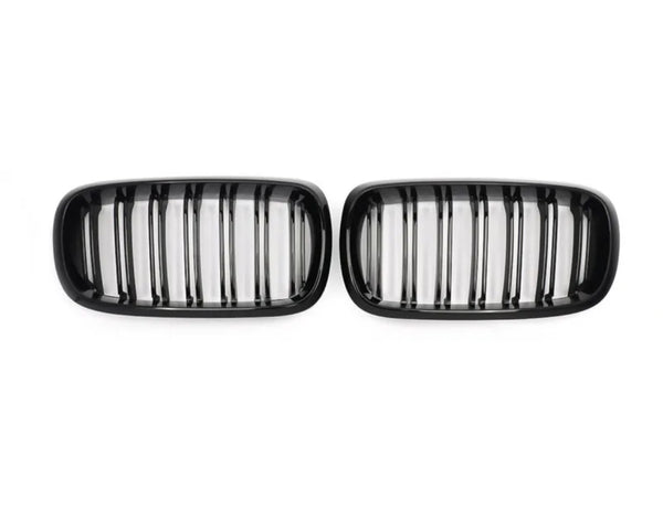 Two black car grilles, each with vertical slats, are positioned side by side against a plain white background.