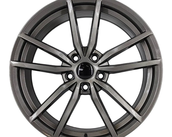 A metallic alloy wheel with intricate spoke design is centered on a plain white background, displaying a modern, sleek appearance, highlighting its detailed craftsmanship and shiny finish.