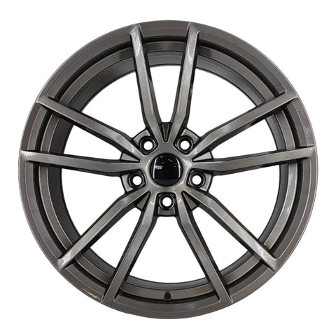 A metallic alloy wheel with intricate spoke design is centered on a plain white background, displaying a modern, sleek appearance, highlighting its detailed craftsmanship and shiny finish.