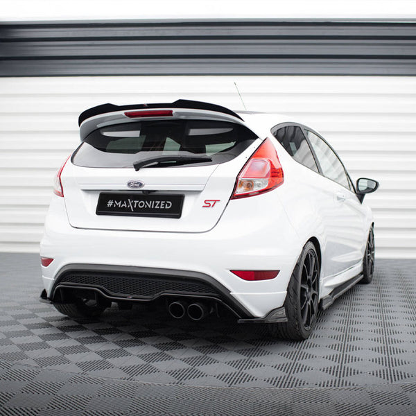 A white Ford hatchback with "ST" badge is parked on a checkered floor in an enclosed, light-colored garage. License plate reading "#Maxtonized."