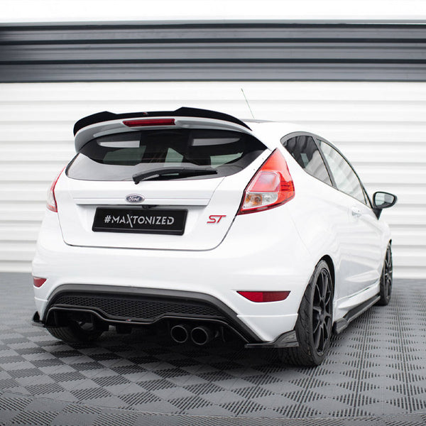 A white Ford car with "#MAXTONIZED" on its license plate is parked in a checkered room, featuring sporty black wheels and a prominent rear spoiler.
