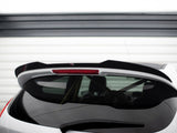 A white car's rear hatch with a black spoiler, featuring a centered red brake light, is parked in front of a white garage door with horizontal panels.