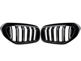 Two black car grille inserts with vertical slats are positioned symmetrically. They rest against a plain white background, showing a sleek, glossy finish.