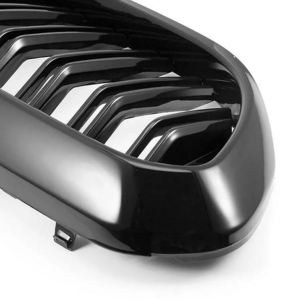 A glossy black car grille features parallel slats, resting against a plain white background.