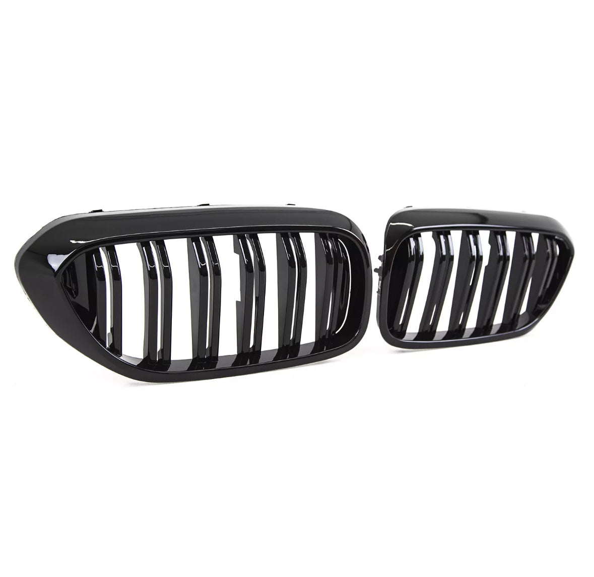 Two glossy black car grilles, featuring vertical slats, are positioned against a plain white background, highlighting their sleek and modern design.