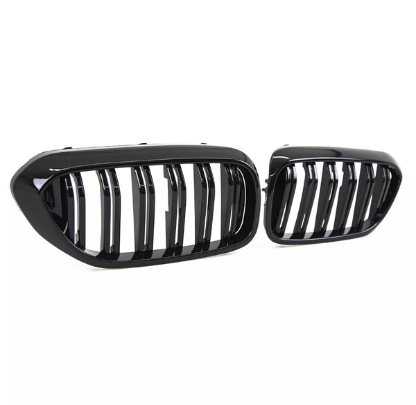 Two glossy black car grilles, featuring vertical slats, are positioned against a plain white background, highlighting their sleek and modern design.