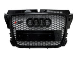 Car grille with a black honeycomb pattern featuring four interlocking rings logo and 