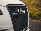 A car's front grille displays the Audi logo and 