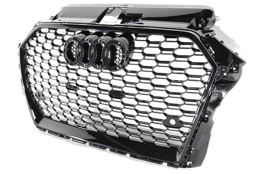 A black car grille showcases interlocking silver hexagonal patterns with a prominent set of four interlinked rings in the center, symbolizing a well-known automotive brand.