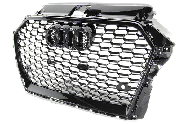 A black car grille showcases interlocking silver hexagonal patterns with a prominent set of four interlinked rings in the center, symbolizing a well-known automotive brand.