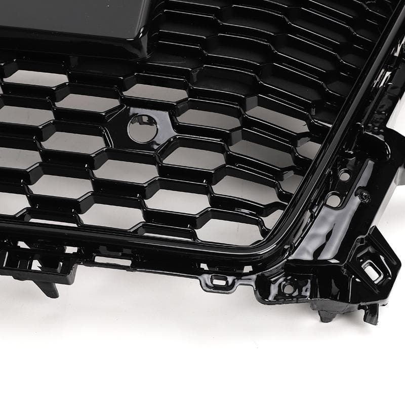 A black, honeycomb-patterned car grille with glossy finish, displayed at an angle on a plain white background.