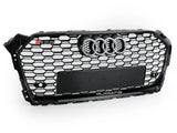 A black Audi car grille with a honeycomb pattern features a chrome Audi emblem, 